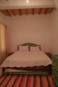 um quarto com uma cama grande e lençóis brancos em coooperative_ogandou_skoura em Skoura