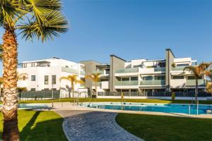 un edificio con una piscina y una palmera en A&N Alexia, en Caleta de Vélez