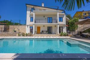 a villa with a swimming pool in front of a house at Luxury Kvarner Park Villa with garden and large RGB private pool in Kastav
