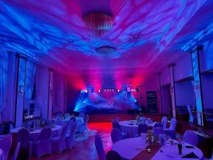 ein Zimmer mit weißen Tischen, Stühlen und lila Leuchten in der Unterkunft Hotel Sächsisches Haus in Berggiesshübel