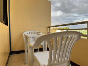 a balcony with two white chairs and a table at HRS APARTELLE in Talisay