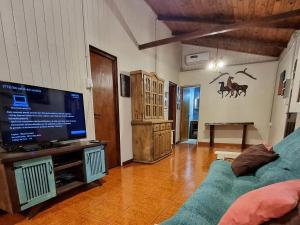 - un salon avec une télévision et un canapé bleu dans l'établissement La Casa Del Lago URUGUA-Í, à Puerto Iguazú