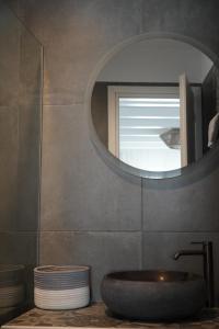a bathroom with a sink and a round mirror at Azul Houses Kythnos in Kithnos +86 photos