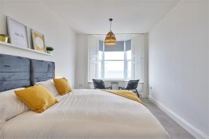 a bedroom with a large bed with two chairs at 5 Roker Terrace - Seaview apartments in Sunderland