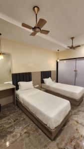 two beds in a room with a ceiling fan at Peace International in Mumbai