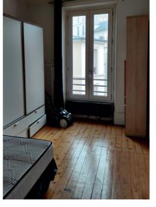 a room with a bed and two windows and a wooden floor at A 10 minutes à pied du stade de France , 35 m2 très cosy refait à neuf in Saint-Denis