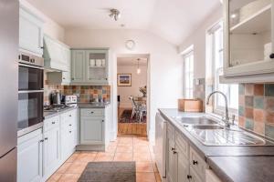 eine Küche mit weißen Schränken und einem Waschbecken in der Unterkunft The Old Rope House in Southwold