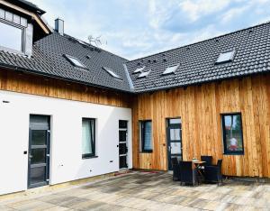 a house with a wooden wall and a patio at Apartmán Jestřábí Lipno in Černá v Pošumaví