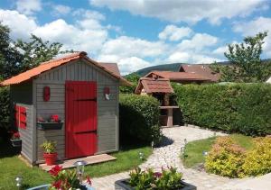 Une petite porte rouge dans une cour dans l'établissement Maison de vacances "Les clefs du pont des fées", à Gérardmer