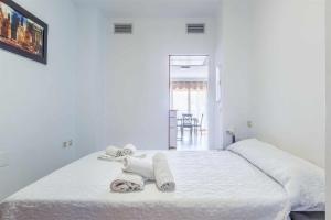 a white bedroom with a bed with towels on it at A&N Caleta de Vélez Marina Retreat in Caleta De Velez