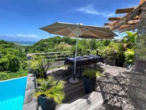 - une table avec un parasol sur une terrasse à côté de la piscine dans l'établissement La Voile Grise - Villa de charme - Sea View, au Gosier