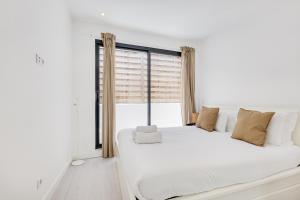 um quarto com uma grande cama branca com janela em Alcantara Charm 3BR Apartments em Lisboa