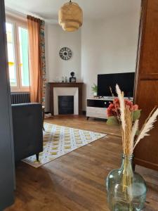 una sala de estar con un jarrón con flores. en MAISON AMPERE, en Limoges