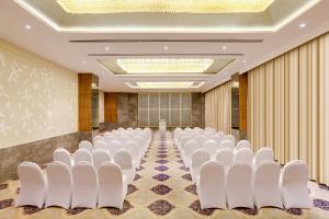 a conference room with white chairs and a wall at Lemon Tree Hotel, Sector 68, Sohna Road, Gurugram in Gurgaon