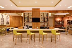 a bar in a restaurant with yellow chairs and a counter at Lemon Tree Hotel, Sector 68, Sohna Road, Gurugram in Gurgaon