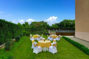 a group of tables and chairs in a garden at Lemon Tree Hotel, Sector 68, Sohna Road, Gurugram in Gurgaon