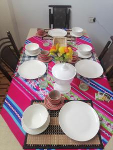 una mesa con platos blancos y cuencos en ella en Apartamento sombras del titicaca, en Puno