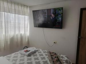 1 dormitorio con TV en la pared y 1 cama en Apartamento sombras del titicaca, en Puno