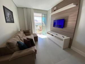 sala de estar con sofá y TV de pantalla plana en Apartamento amplo bem equipado, en João Neiva