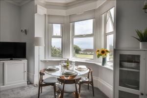 a dining room with a table and chairs and windows at Flat 2, 10 Seafield Road in Seaton