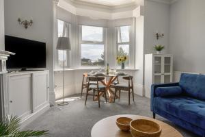 a living room with a blue couch and a table at Flat 2, 10 Seafield Road in Seaton