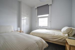2 łóżka w białym pokoju z oknem w obiekcie Flat 2, 10 Seafield Road w mieście Seaton