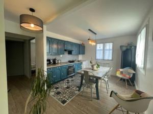 Una cocina con gabinetes azules y una mesa y sillas. en Bel Appartement dans résidence cheminée /Jardin, en Luz-Saint-Sauveur