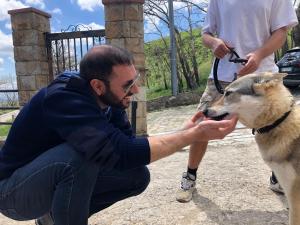 un hombre acariciando un perro en un zoológico en Rifugio SHIVA, en Petralia Soprana