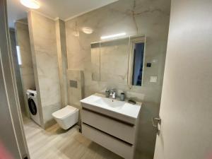 a bathroom with a white sink and a toilet at Modern Living Experience in Néa Péramos +20 photos