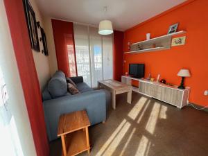 sala de estar con paredes de color naranja y sofá azul en Apartamento Mirando al Mar, en Canet de Berenguer