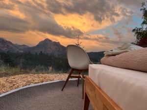 a bedroom with a bed and a chair and mountains at Bubble Tent Füssen im Allgäu in Füssen