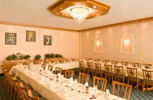 ein Bankettsaal mit Tischen und Stühlen und einem Kronleuchter in der Unterkunft Moselstern Hotel Brixiade &Triton in Cochem