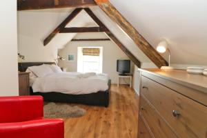 a bedroom with a bed and a red chair at Town centre apartment with parking in Padstow
