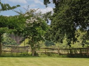 a wooden fence with a tree in a field at Spindlewood Cottage in Cranbrook