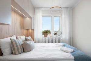 a bedroom with a large white bed with a window at Elite Apartments Sandy in Gdańsk