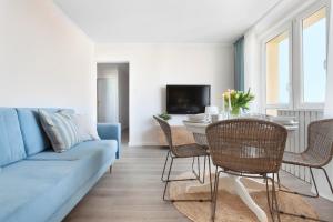 a living room with a blue couch and a table and chairs at Elite Apartments Sandy in Gdańsk