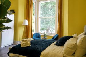 a bedroom with a bed with blue chairs and a window at LUXURY Holiday Home Elizabeth Line in London