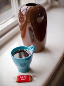 eine Tasse Kaffee auf einer Theke neben einer Vase in der Unterkunft The Llandudno Hotel in Llandudno