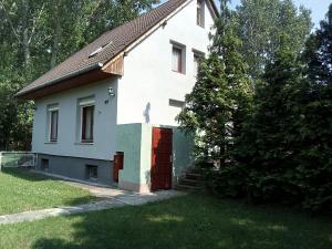 una casa blanca con una puerta roja en un patio en F 106 Vendégház, en Fertőhomok