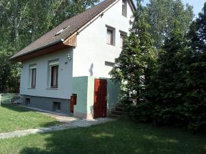 a white house with a red door in a yard at F 106 Vendégház in Fertőhomok