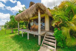 Hotel CasaBakal - A pie de Laguna - Bacalar في باكالار: كوخ صغير بسقف من القش ومقعد