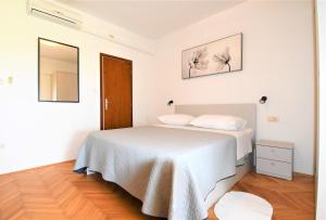a white bedroom with a bed and a mirror at Apartment Lopar 1 in Lopar