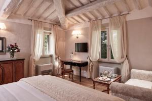 a bedroom with a bed and a desk in it at Villa di Piazzano - Small Luxury Hotels of the World in Cortona