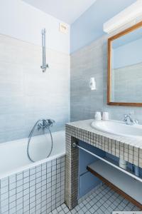 La salle de bains est pourvue d'une baignoire, d'un lavabo et d'un miroir. dans l'établissement Hôtel Édenia - Spa Estime&Sens, à Carnac