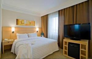 a hotel room with a bed and a flat screen tv at Golden Flat's - Slaviero Guarulhos in Guarulhos