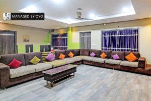 a living room with a large couch with colorful pillows at Super Collection O Urban Guest House in Behāla