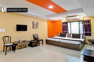 a bedroom with a bed and a desk and a tv at Super Collection O Urban Guest House in Behāla