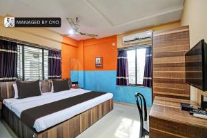 Schlafzimmer mit einem Bett, einem Schreibtisch und einem TV in der Unterkunft Super Collection O Urban Guest House in Behāla