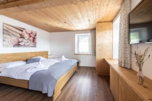 una camera con letto e soffitto in legno di La Tgoma - Hotel & Restaurant a Lenz