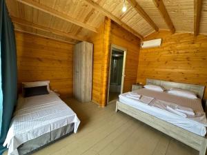 a bedroom with two beds in a wooden cabin at Эко-комплекс More in Gudauta